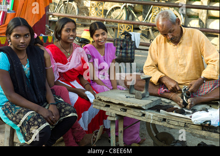 Les filles indiennes en magasin de chaussures avec cordonnier au travail à Sarnath, près de Varanasi, Benares, Inde du Nord Banque D'Images