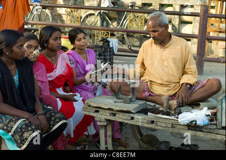 Les filles indiennes en magasin de chaussures avec cordonnier au travail à Sarnath, près de Varanasi, Benares, Inde du Nord Banque D'Images