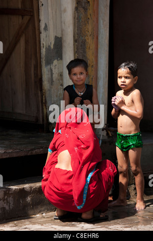 Les enfants indiens d'être baigné avec de l'eau d'un robinet dans la rue par leur mère dans Agra, Inde Banque D'Images