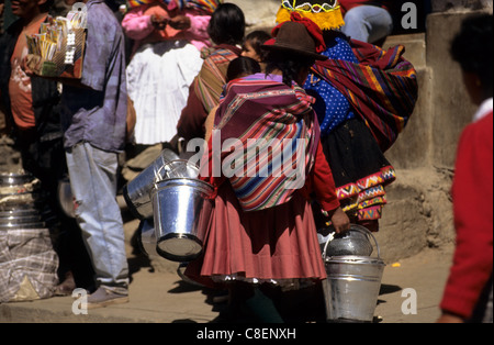 Paucartambo, Pérou. Femme portant un costume traditionnel et de transporter des seaux galvanisés par l'arrière. Banque D'Images