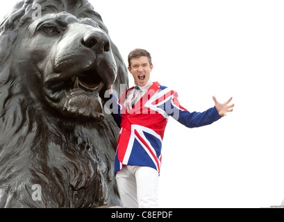 Jeune homme portant un drapeau de l'Union à côté de la veste de roaring lion statue, Trafalgar Square, Londres, Angleterre Banque D'Images