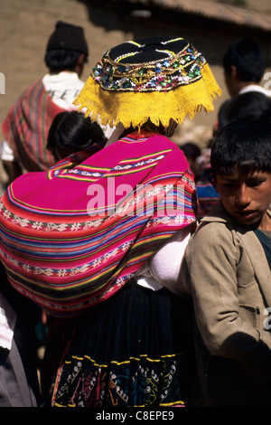 Paucartambo, Pérou. Femme portant un costume traditionnel et portant un bébé dans une mante sur son dos. Banque D'Images