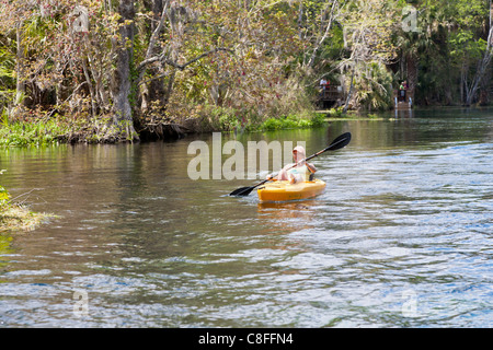 Jeune femme en kayak Kayak orange sur la rivière d'argent près de Silver Springs Attractions touristiques dans la région de Ocala en Floride Banque D'Images