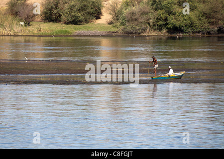 Deux pêcheurs de petit bateau dans les eaux peu profondes du Nil, l'Egypte, l'un assis l'autre barques à fond avec la banque dans l'arrière-plan Banque D'Images