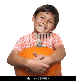 Jeune garçon souriant tout en enroulant ses bras autour d'un grand pumpkin on white background with copy space Banque D'Images