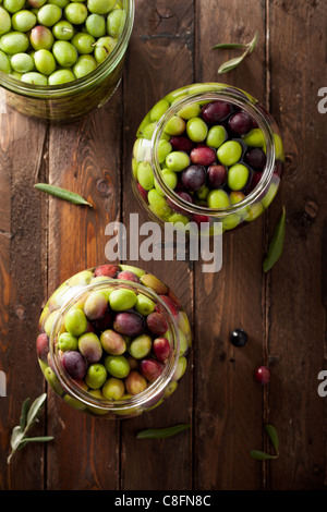 Olives en saumure (avec de l'eau et le sel dans un bocal en verre) sur bois Banque D'Images