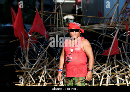 Chemise rouge gardien de sécurité en face de barricade faite de pneus, le fil barbelé, & poteaux de bambou, Red shirt protestation, Bangkok, Thaïlande. © Kraig Lieb Banque D'Images