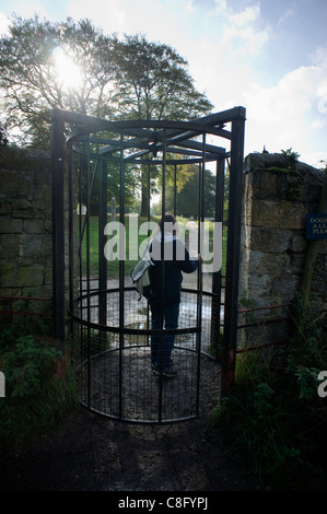 Femme Walker marche par le Cannon Kissing Gate à l'entrée du domaine de Chatsworth Derbyshire Peak District Banque D'Images