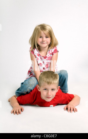 Deux des enfants de race blanche s'amusant avec 7 ans, assis sur le dessus de 8 ans frère Banque D'Images