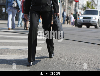 Les jambes de femme comme elle marche dans l'urgence alors qu'elle est de traverser la rue. Banque D'Images