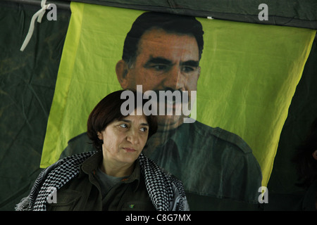 Portrait de l'Union des communautés du Kurdistan (KCK) Membre du Conseil exécutif Sozdar Avesta avec la figure de l'ancien militant du PKK, Abdullah Ocalan, leader en arrière-plan dans un camp du nord de l'Iraq hideout PKK Banque D'Images