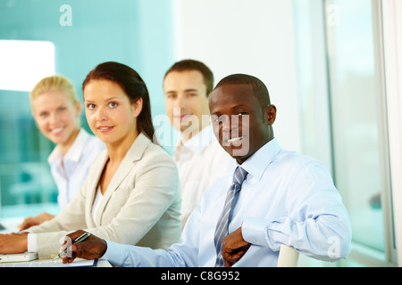 Quatre businesspeople in office looking at camera and smiling Banque D'Images