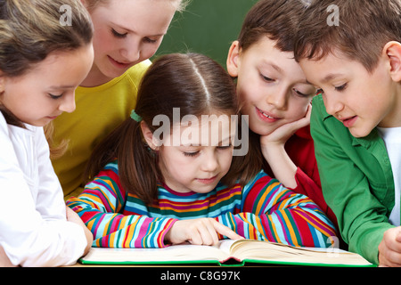 Portrait de groupe sympathique reading book in classroom Banque D'Images