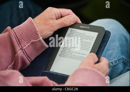 Man reading book sur Amazon Kindle ebook reader Banque D'Images