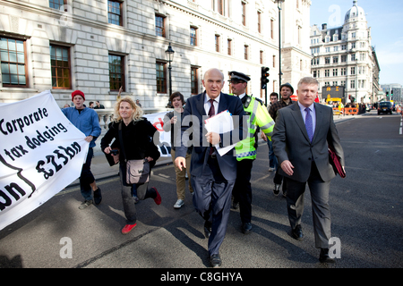 Vince Cable, le secrétaire d'entreprise, est confrontée par des manifestants opposés à la "l'évasion fiscale de l'entreprise' pendant qu'il marche de Whitehall à Victoria Street, dans le centre de Londres, Royaume-Uni, le lundi 24 octobre, 2011. Banque D'Images