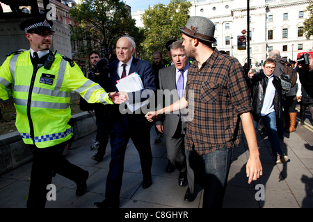 Vince Cable, le secrétaire d'entreprise, est confrontée par des manifestants opposés à la "l'évasion fiscale de l'entreprise' pendant qu'il marche de Whitehall à Victoria Street, dans le centre de Londres, Royaume-Uni, le lundi 24 octobre, 2011. Banque D'Images