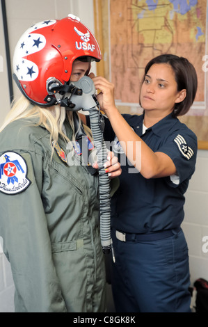 Sergent d'état-major Robbin Bailon, une technicienne en équipement de vol de la Force aérienne Thunderbirds, ajuste le casque et le masque facial sur Megan Funk pendant son costume de vol en tenue le 4 juin à la base aérienne de Hill, Utah. Mme Funk, enseignante de deuxième année à l'école primaire Majestic d'Ogden, Utah, a été sélectionnée comme héros de sa ville natale pour son service bénévole dans la communauté pour laquelle elle a reçu un vol dans un faucon de combat Thunderbird F-16. Banque D'Images