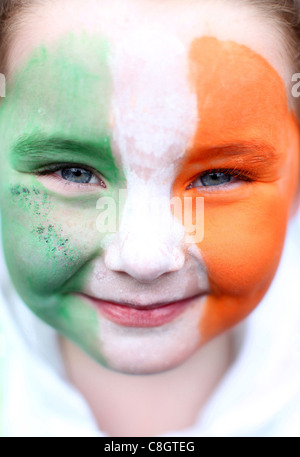 Une des jeunes filles avec le drapeau irlandais peint sur son visage sourit pendant le défilé de jour de Saint Patrick à Dublin, Irlande Banque D'Images