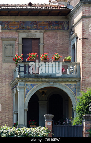 Un balcon avec des fleurs rouges sur une brique arch, Sienne, Italie Banque D'Images