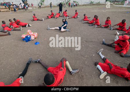 Shahaf PRI-Paz un volontaire israélien de Natan qui participe à un exercice physique avec de jeunes enfants lors d’une séance d’instruction de football dans un camp de fortune à Port-au-Prince qui accueille des milliers de personnes depuis que le séisme de magnitude 7,0 a frappé Haïti le 12 janvier 2010 Banque D'Images