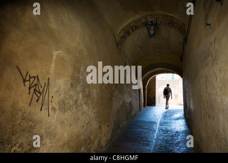 Un randonneur promenades à travers un tunnel avec graffiti, Sienne, Italie Banque D'Images