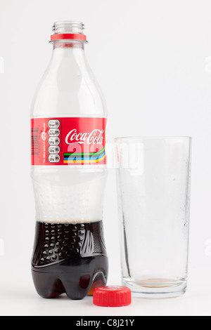 En partie en plastique vide bouteille de Coca-Cola et un verre plein utilisé vide Banque D'Images