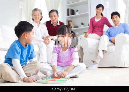 Enfants jouant avec des jouets chinois sur le sol avec les grands-parents et les parents derrière eux Banque D'Images