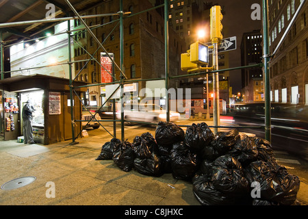 New York City coin de rue la nuit. Newstand et sacs poubelle à l'angle de la Place de la Trinité & Exchange Place à Manhattan Banque D'Images