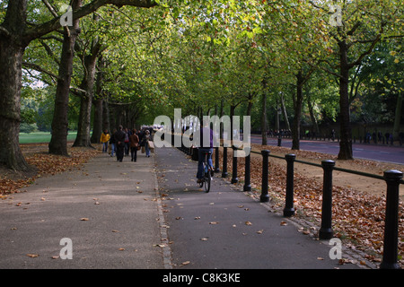 Personnes à pied et un cycliste vélo le long d'un chemin aux côtés de Constitution Hill, Green Park, Londres Banque D'Images