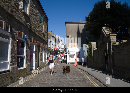 St Ives Cornwall England UK Woman walking trois chiens en laisse le long de place du marché dans cette station balnéaire de Cornouailles Banque D'Images