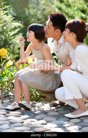 Family blowing Bubbles in garden Banque D'Images