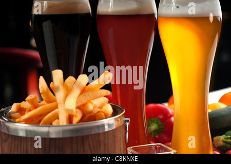 Frites fraîches sur un seau en bois avec sélection de bières et de légumes frais sur l'arrière-plan Banque D'Images