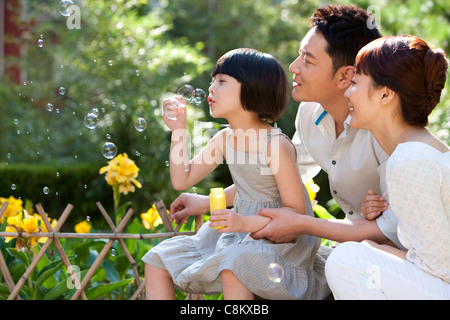 Family blowing Bubbles in garden Banque D'Images