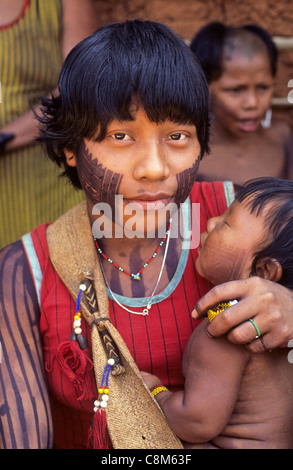 Un Ukre - village, Xingu, au Brésil. Les jeunes Indiens Kayapo femme avec son enfant ; la face noire de la peinture. Banque D'Images