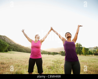 Les femmes athlétiques standing in field with arms raised Banque D'Images