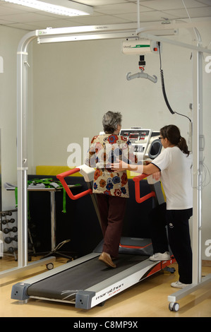 Physiothérapeute aide femme marche sur tapis roulant sur gymnase de réadaptation physique Banque D'Images
