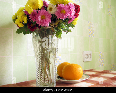 Still Life : vase avec asters et la plaque avec les oranges sont sur une table Banque D'Images