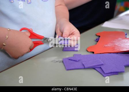 Enfant maternelle l'apprentissage de l'utilisation d'une paire de ciseaux at nursery Banque D'Images