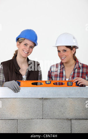 Deux femme s'élevait par wall holding spirit level Banque D'Images