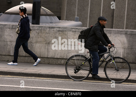 Un cycliste vélo d'une façon et un homme marchant dans la direction opposée à Londres Banque D'Images