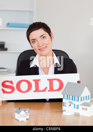 Real estate agent avec un panneau vendu et maisons miniatures Banque D'Images