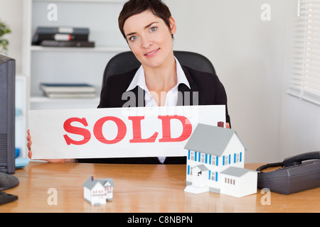 Agent immobilier femelle avec un panneau vendu et maisons miniatures Banque D'Images