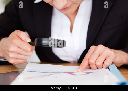 Les mains tenant une loupe au-dessus d'un graphique Banque D'Images