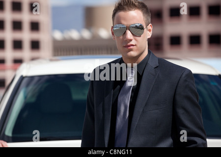 Portrait of handsome young businessman wearing costume et cravate dans la ville, en face de sa voiture. Banque D'Images