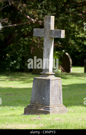 Pierre tombale Crucifix fixé dans l'herbe avec d'autres pierres tombales du cimetière en arrière-plan Banque D'Images