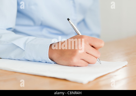 Femme écrivant sur une feuille de papier en position assise Banque D'Images