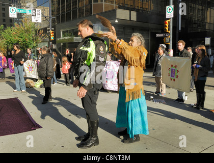 Les femmes des Premières Nations aîné en train une cérémonie de purification par sur un policier de Vancouver. Banque D'Images