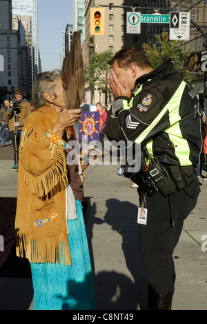 Les femmes des Premières Nations aîné en train une cérémonie de purification par sur un policier de Vancouver. Banque D'Images