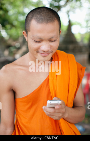 Moine cambodgien text messaging on cell phone Banque D'Images