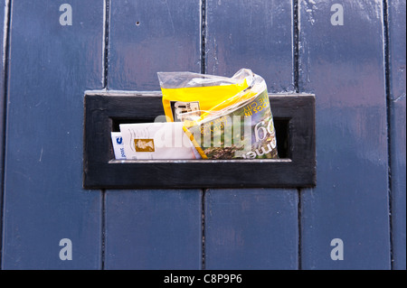 Lettres et mail qui sort d'une boîte aux lettres dans le Royaume-Uni/porte d'une maison Banque D'Images